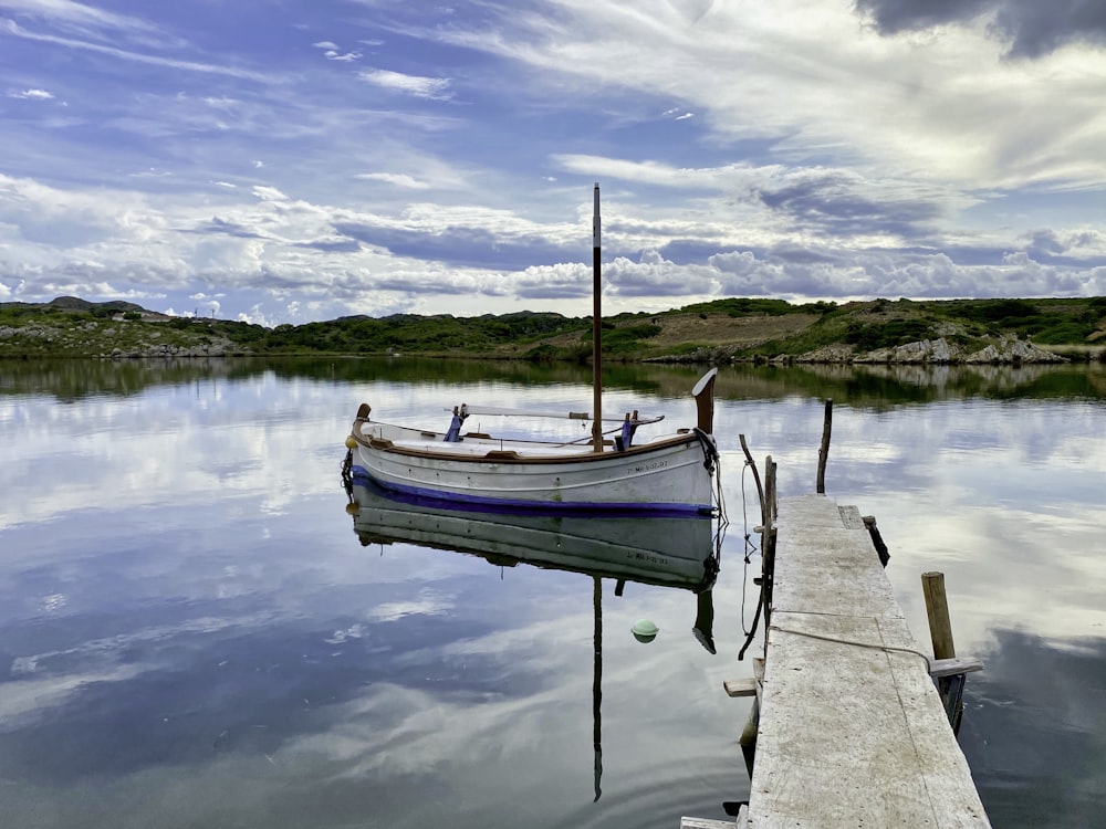 blue and white boat on dock during daytime