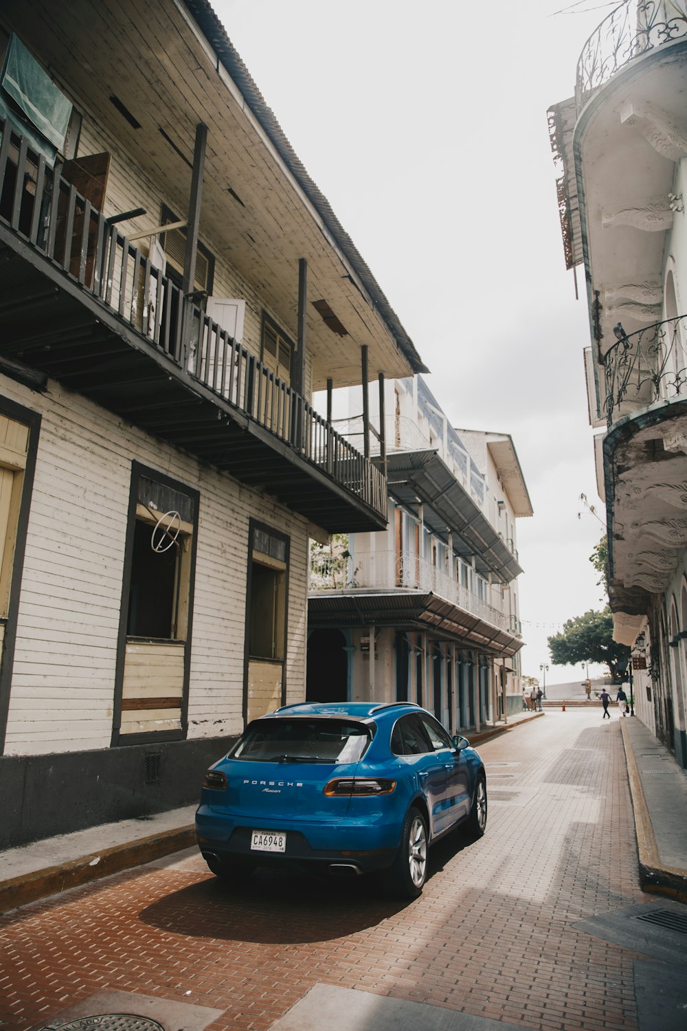 blue car parked beside white and brown concrete building during daytime