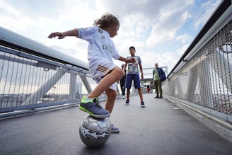 boy in white t-shirt and blue shorts playing soccer during daytime