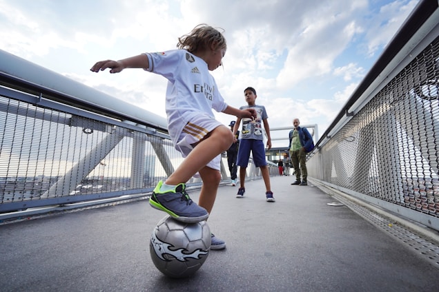 boy in white t-shirt and blue shorts playing soccer during daytime