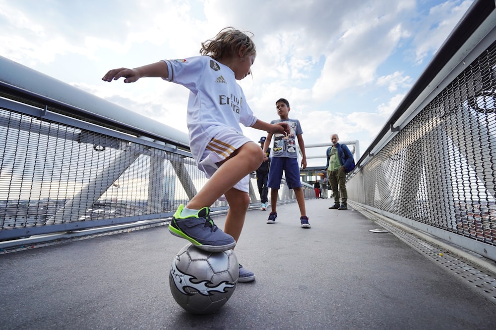 Junge in weißem T-Shirt und blauen Shorts spielt tagsüber Fußball