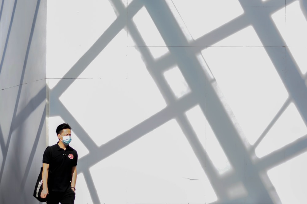 man in black jacket standing beside white wall