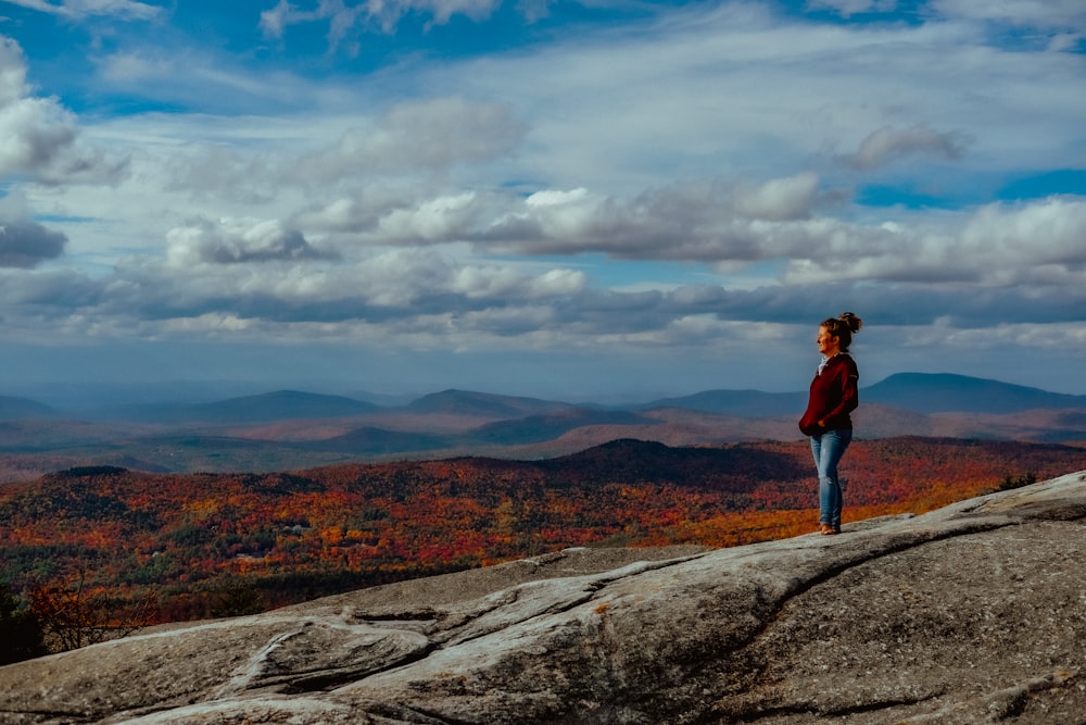 a woman standing on top of a large rock