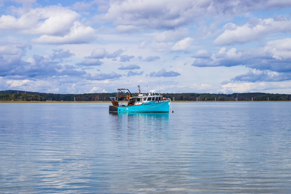 blue and white boat on sea under white clouds during daytime