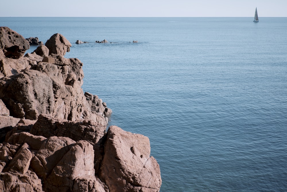 brown rocky mountain beside blue sea during daytime