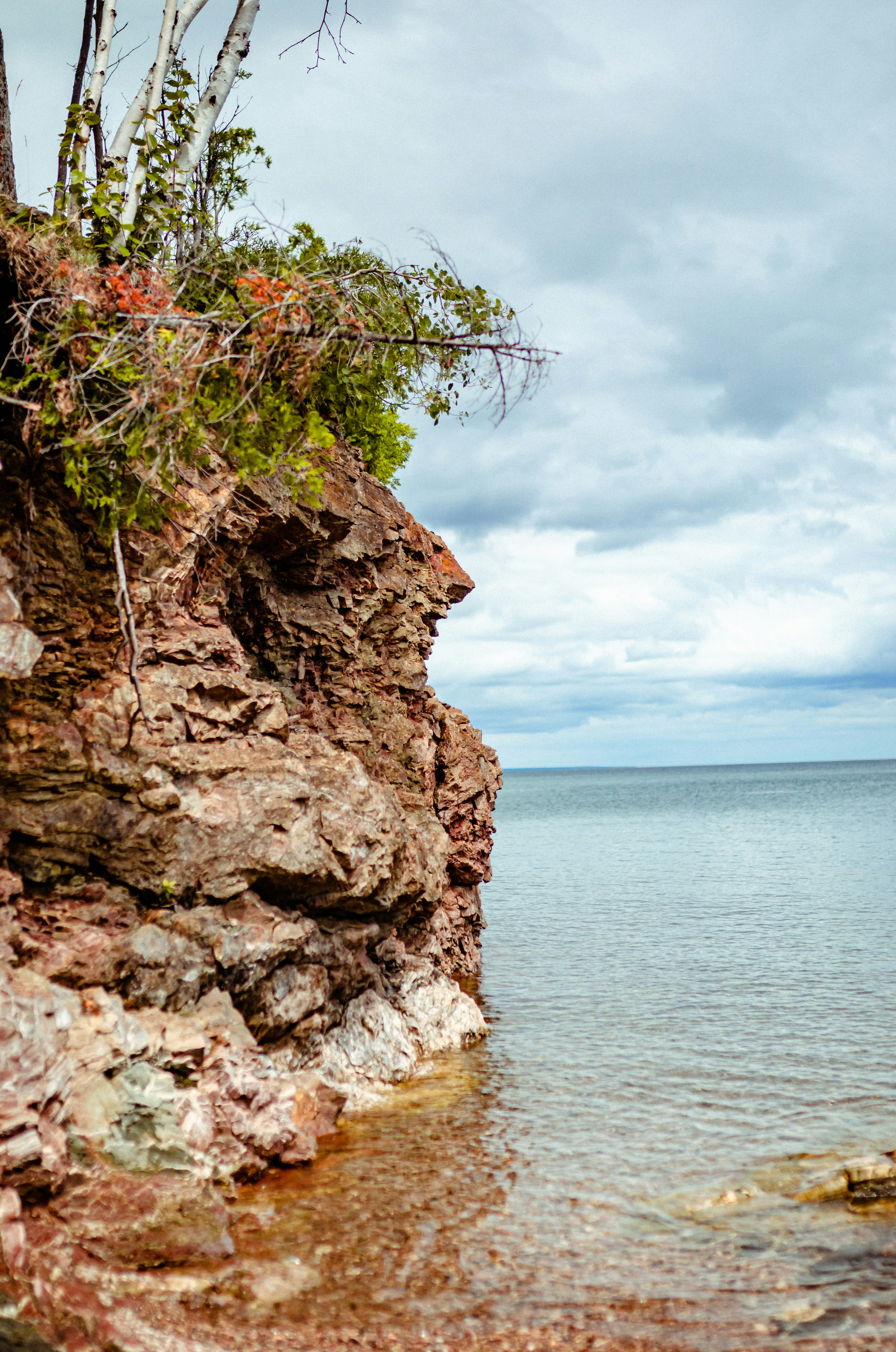 brown rocky mountain beside body of water during daytime