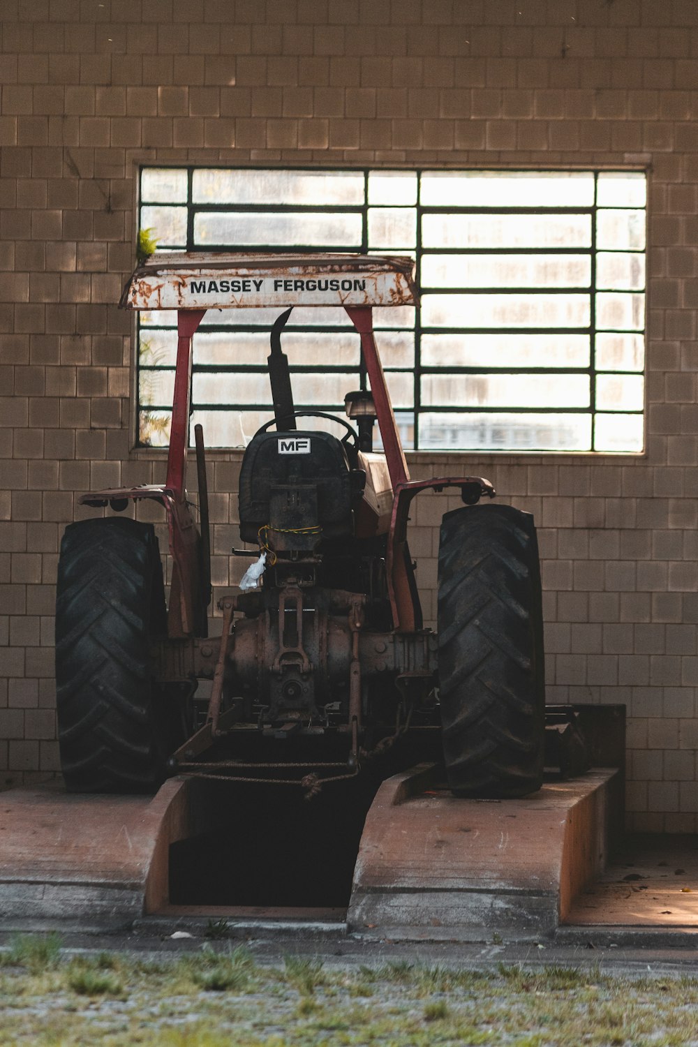 red and black tractor in front of white brick wall