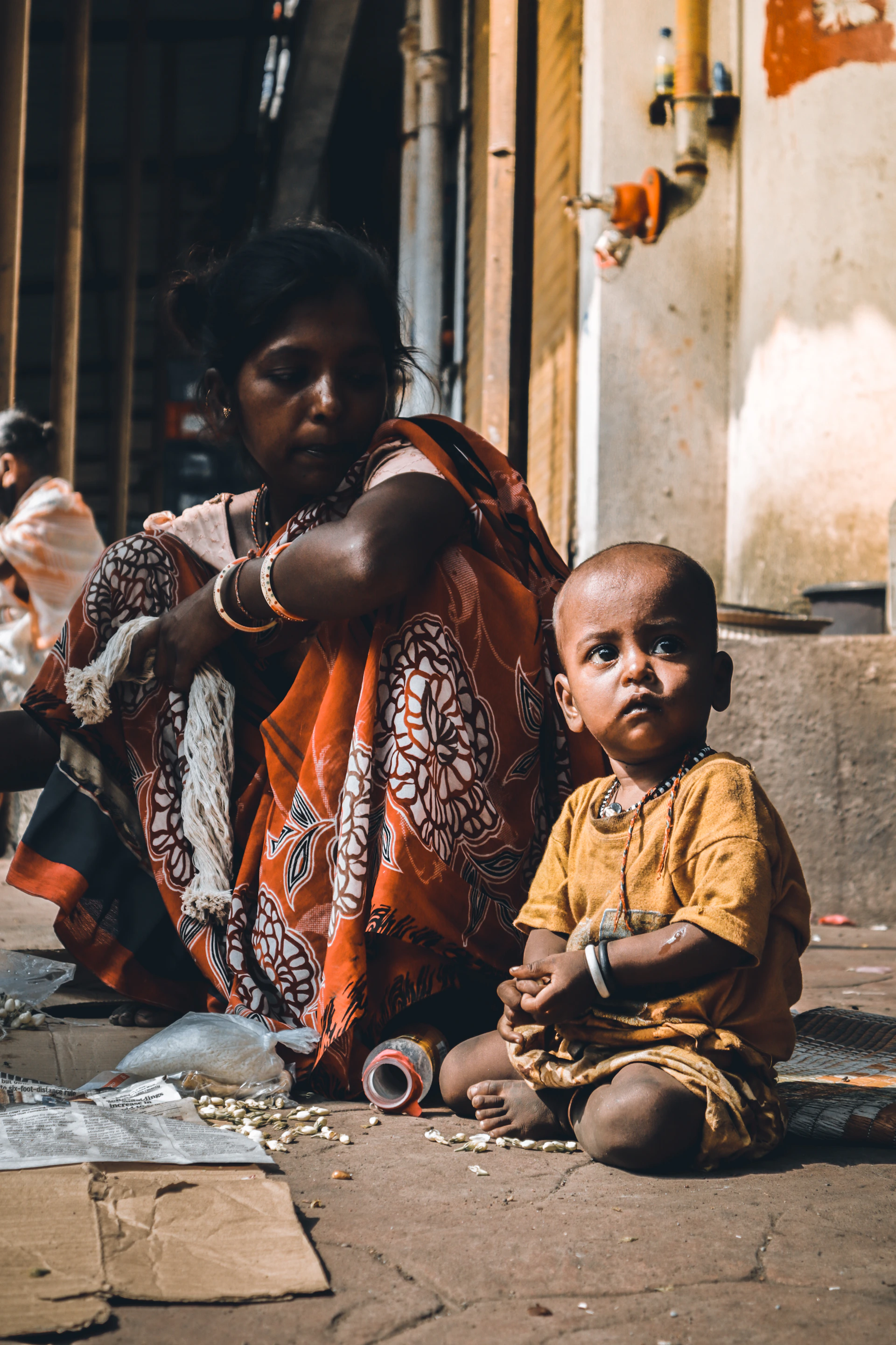 woman in brown and white sari sitting on sidewalk during daytime