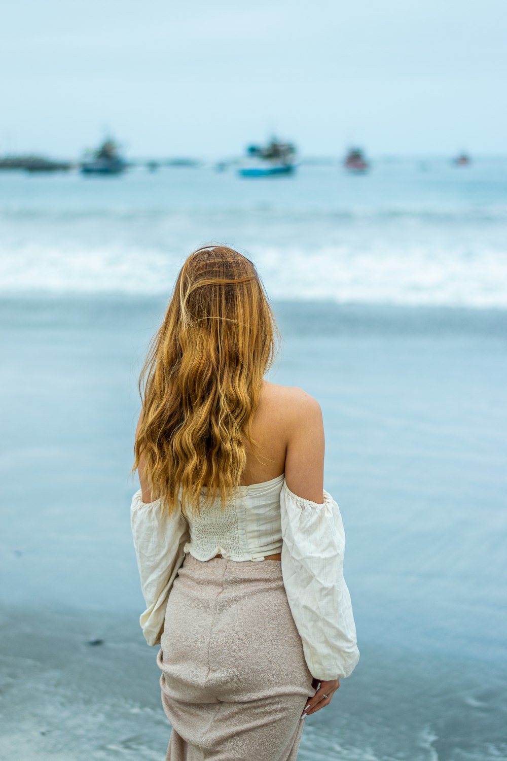 woman in white sleeveless dress standing on beach during daytime