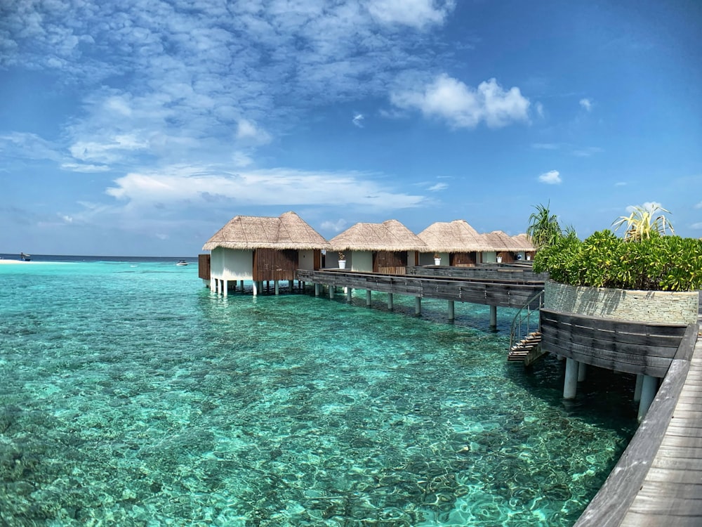 casa di legno marrone sullo specchio d'acqua sotto il cielo blu durante il giorno