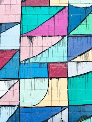 Hand-drawn street art blending bold geometric shapes with smooth wavy lines on a brick wall.