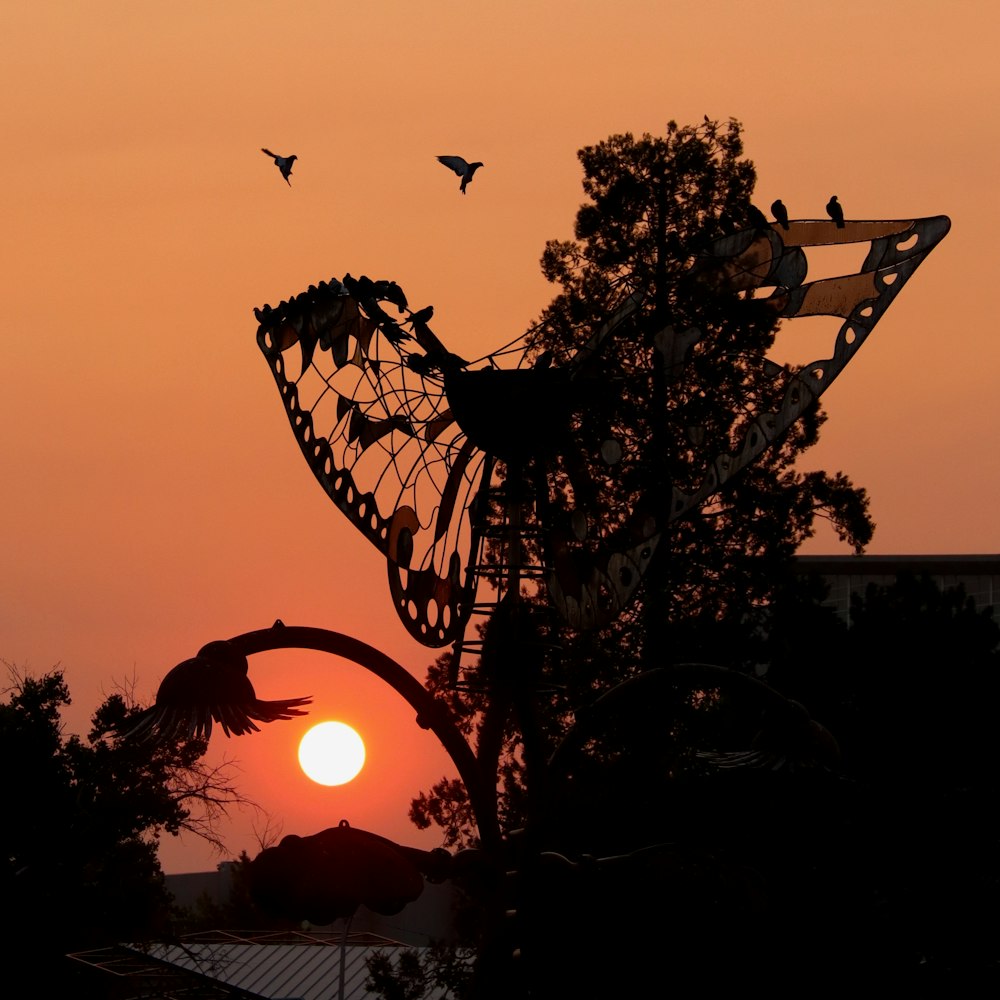 silhouette of birds flying over the tree during sunset