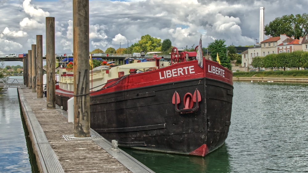 Rotes und schwarzes Boot tagsüber unter bewölktem Himmel