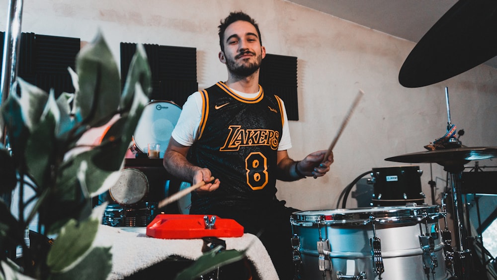 man in black and white nike crew neck t-shirt playing drum