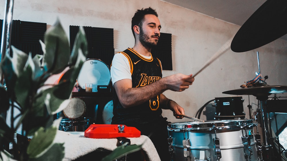 man in white and blue crew neck t-shirt playing drum