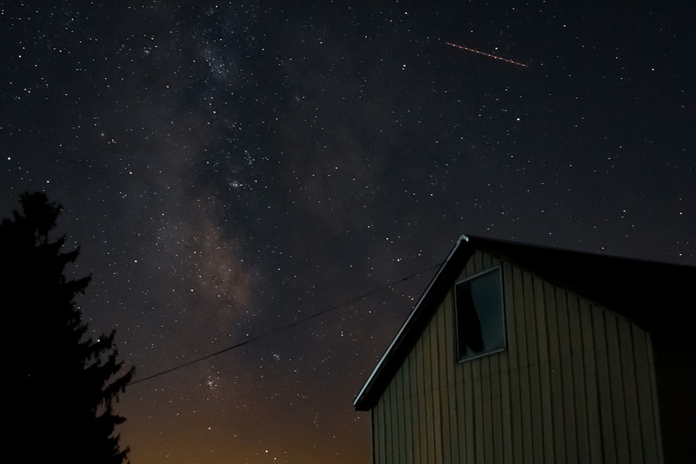 casa di legno marrone sotto la notte stellata