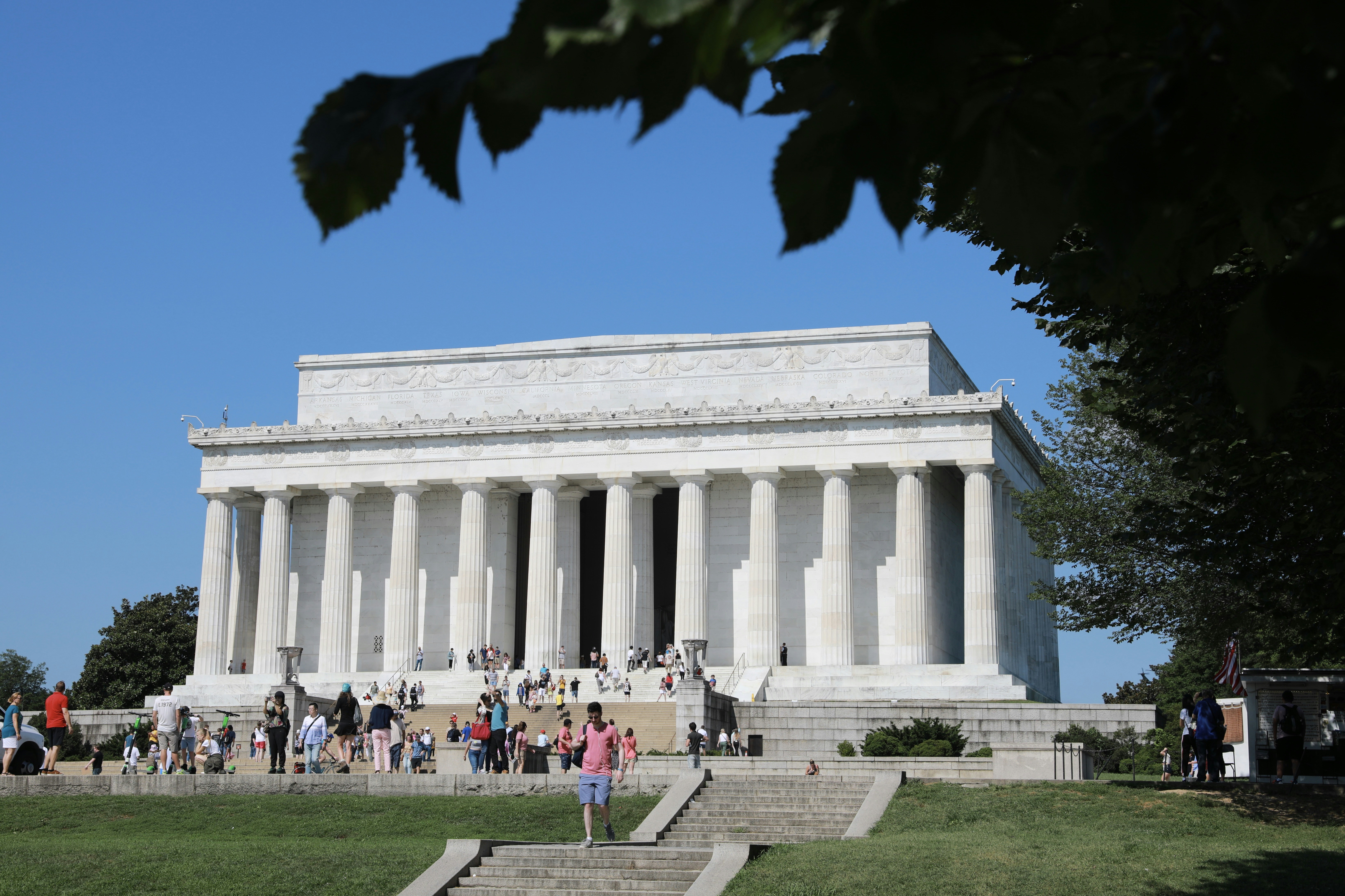people walking in front of white concrete building during daytime lincoln memorial teams background