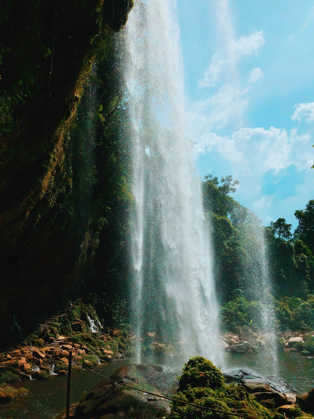 water falls under blue sky during daytime