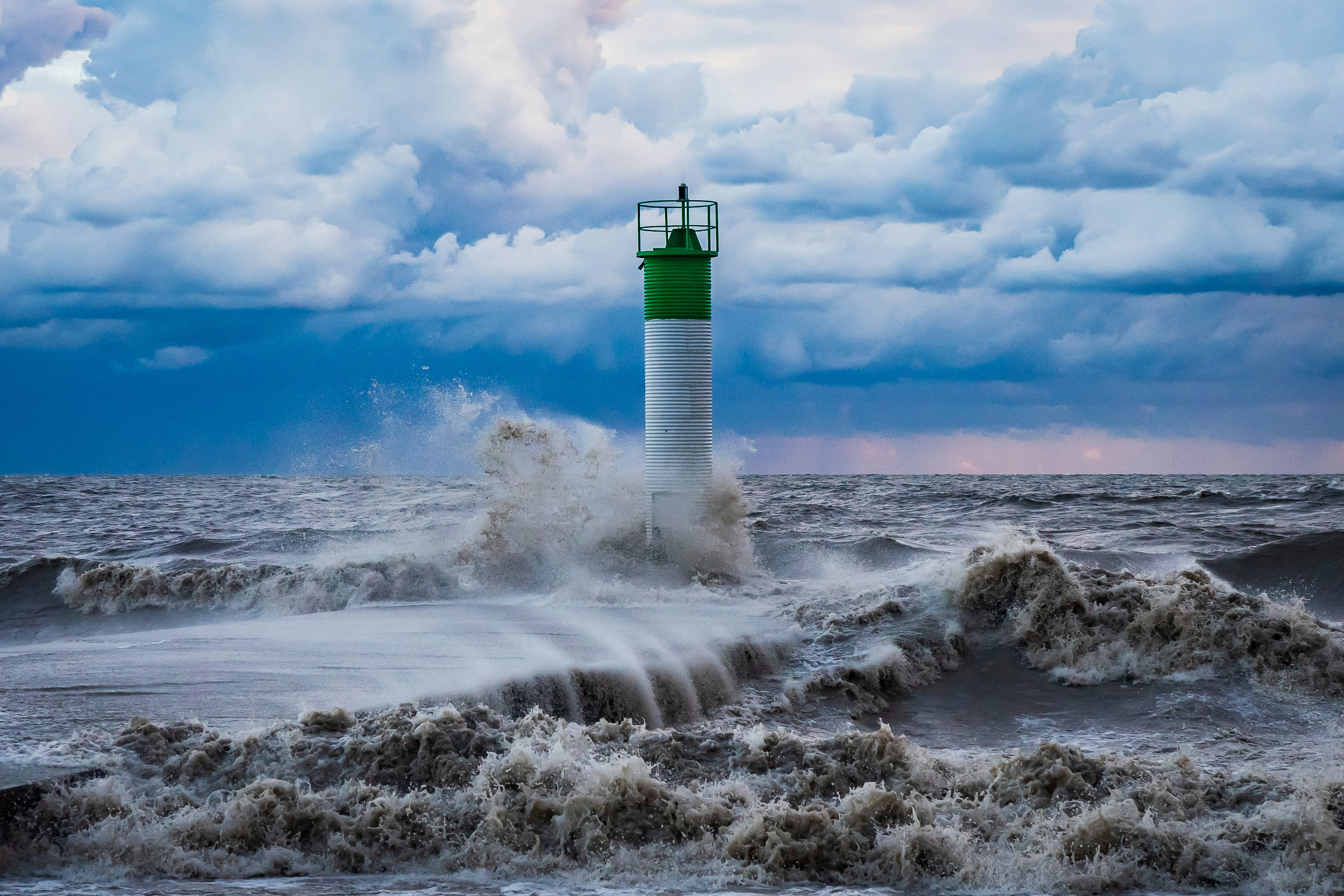 white and green lighthouse on white clouds during daytime