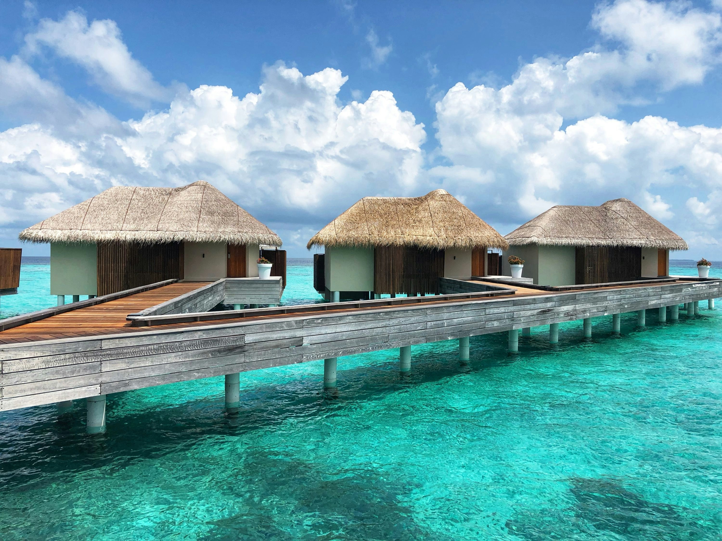 brown wooden house on body of water under blue and white sunny cloudy sky during daytime, Overwater Villa at the W Hotel luxury resort in the Maldives. 