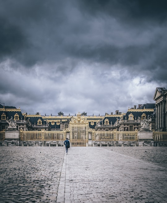 people walking on street near brown concrete building under gray clouds during daytime in Palace of Versailles France