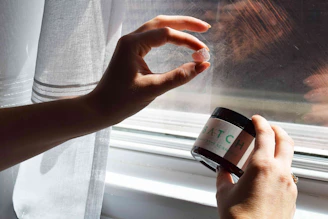 A hand holding a bright, translucent gummy with a blurred natural background.