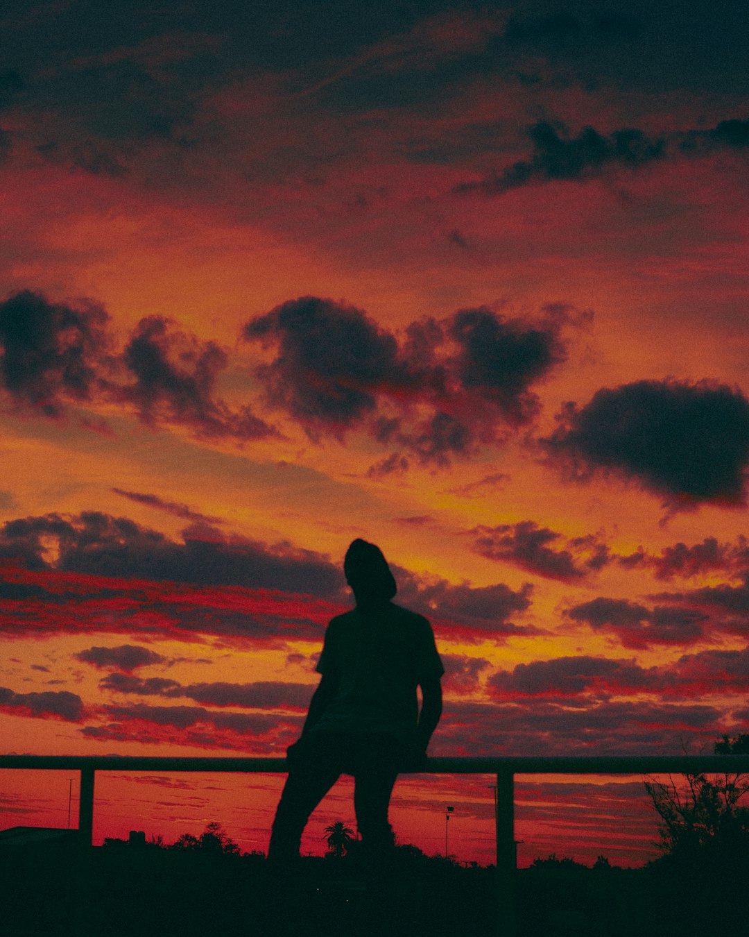 silhouette of man standing on wooden dock during sunset