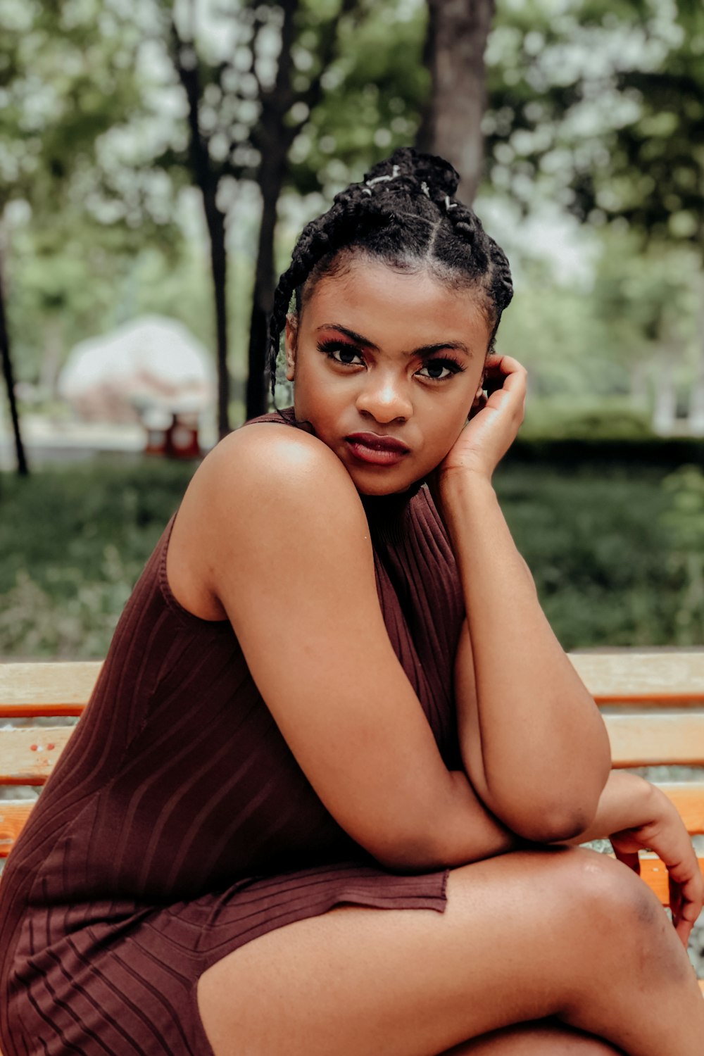 woman in brown sleeveless dress sitting on brown wooden bench