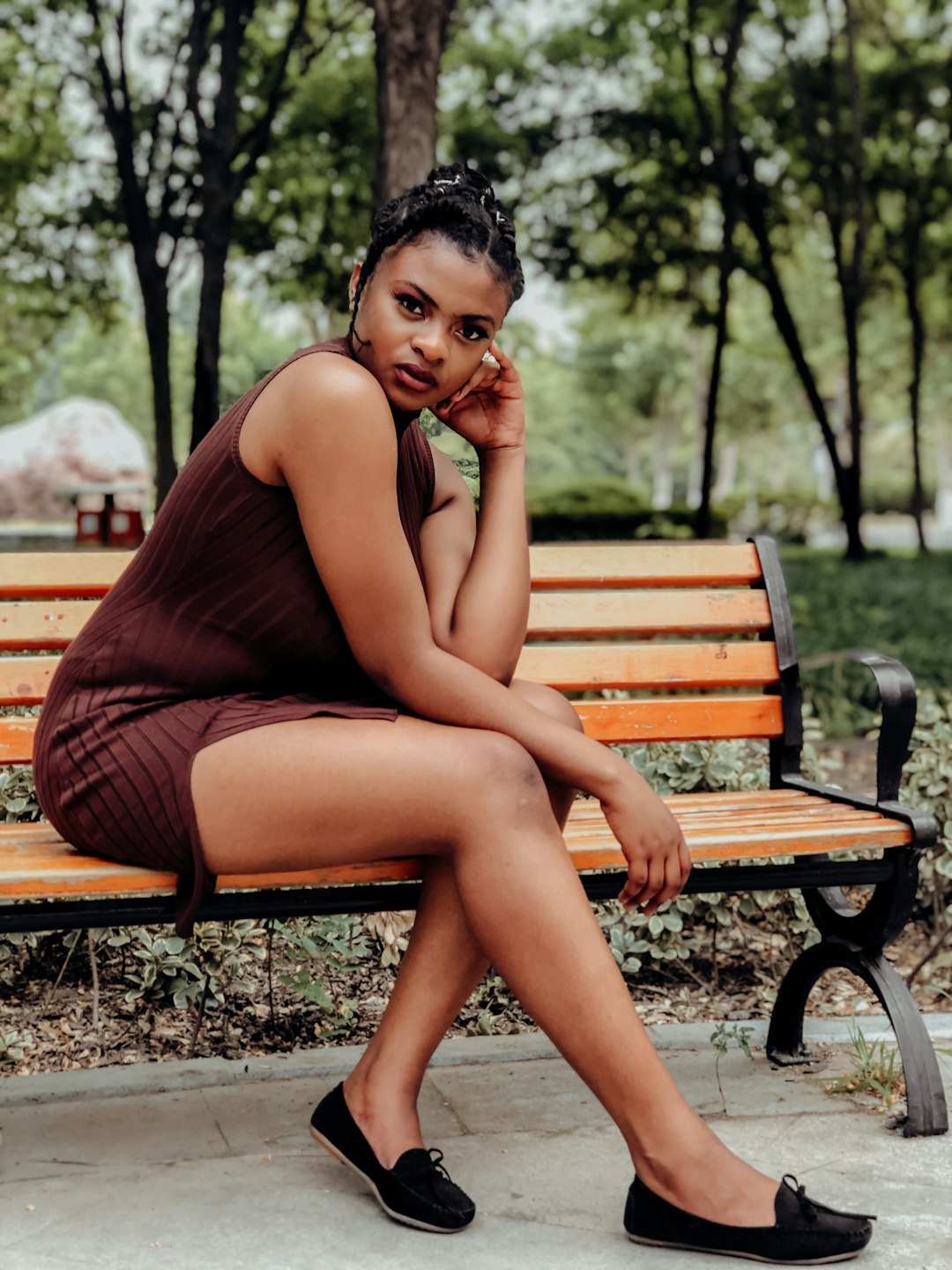 woman in brown tank dress sitting on brown wooden bench