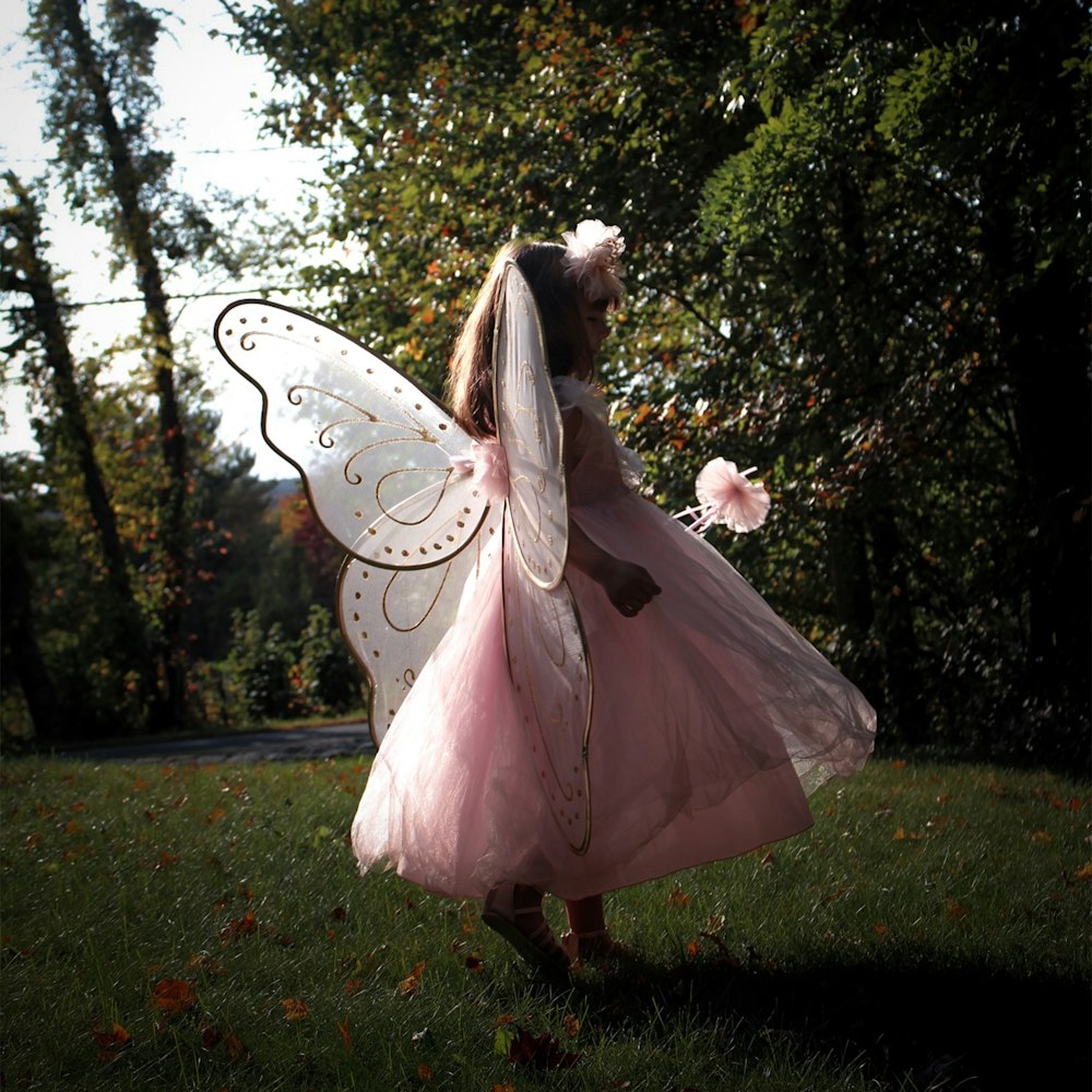 femme en robe blanche debout sur le champ d’herbe verte pendant la journée