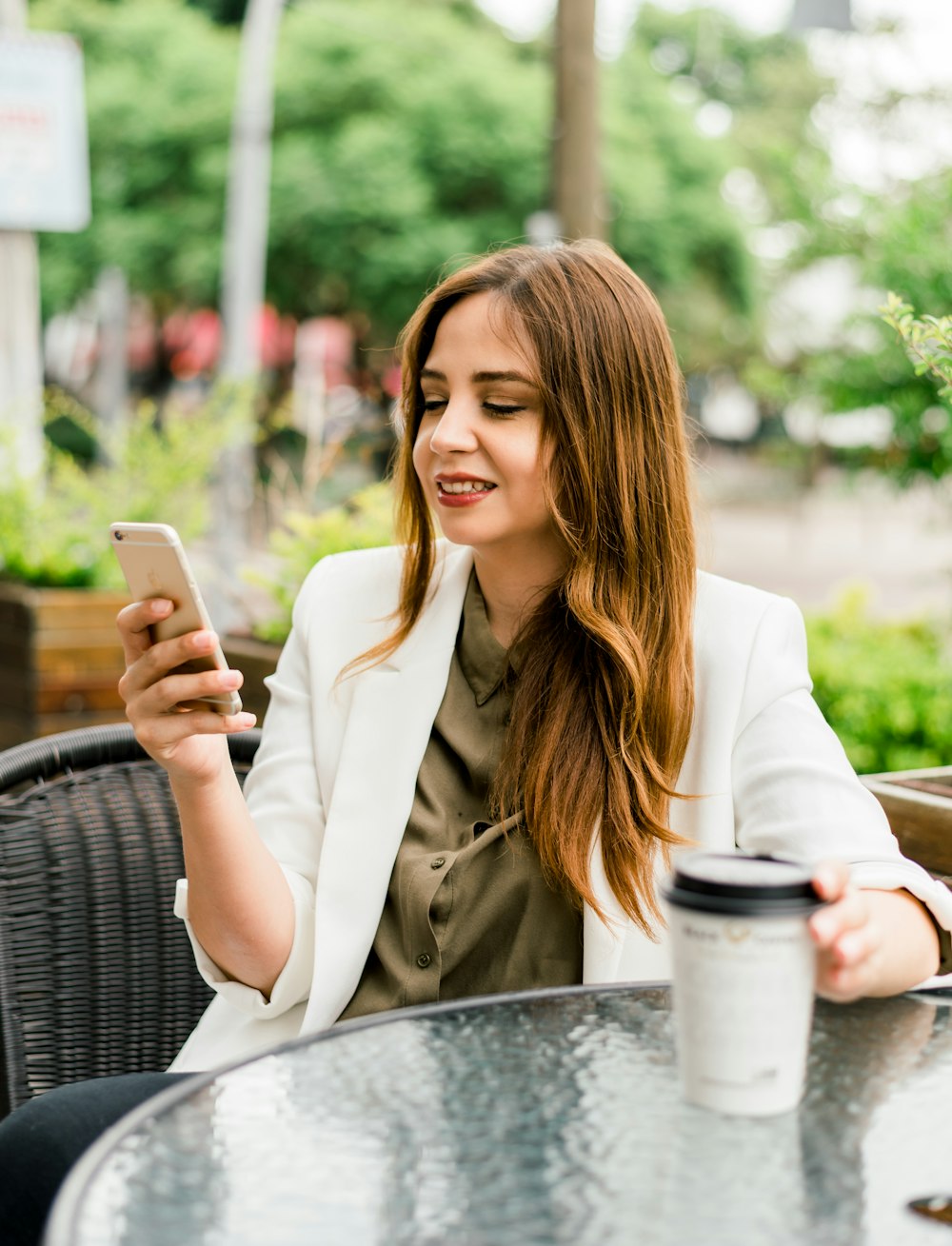 woman in beige blazer holding silver iphone 6