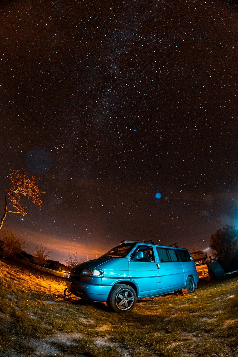 blue suv on brown grass field during night time