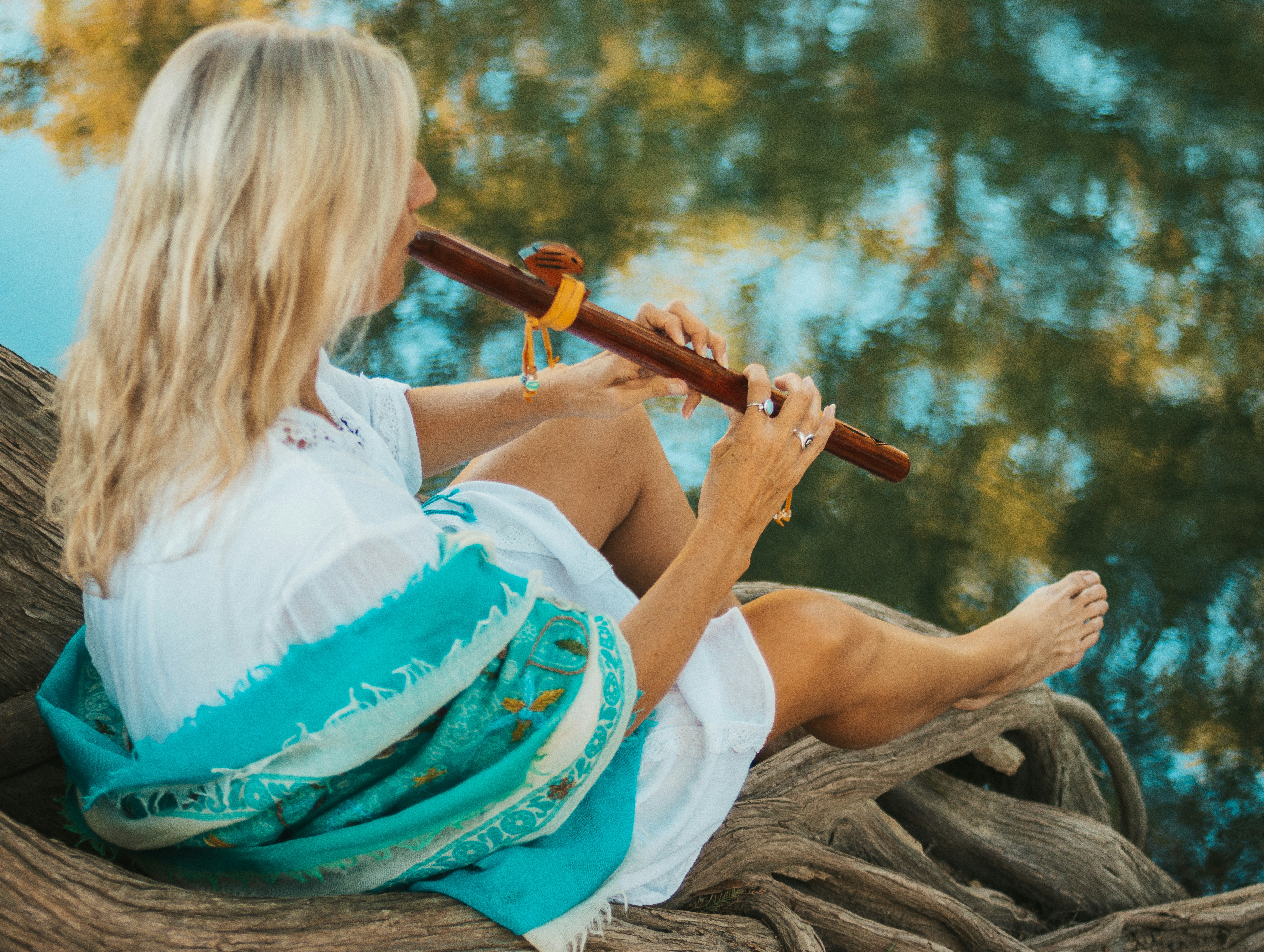 woman in white and teal dress playing flute flute teams background