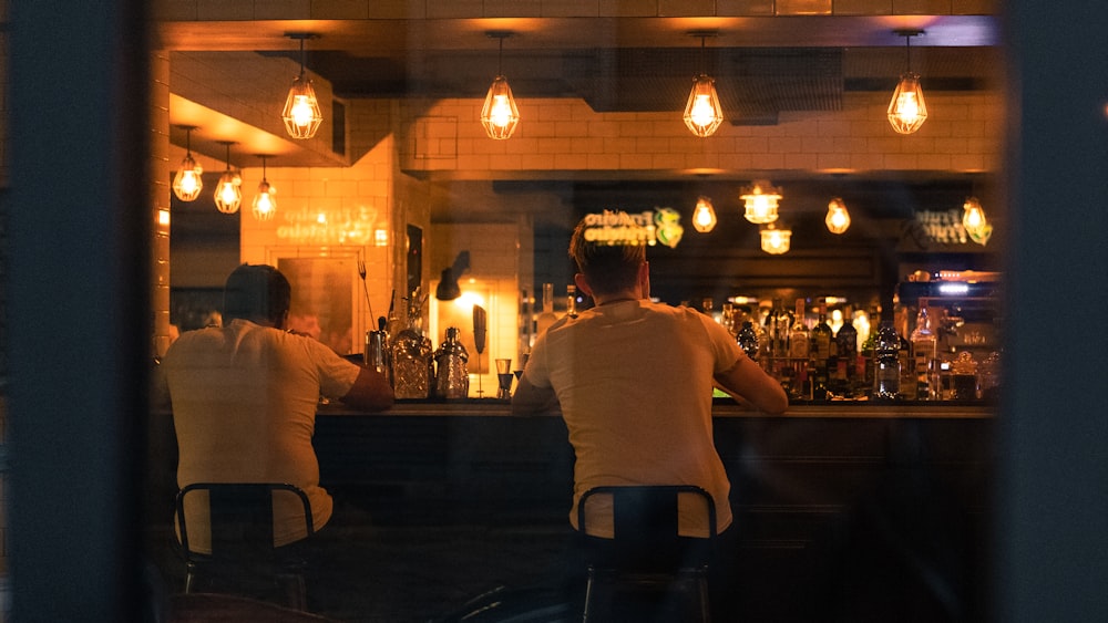 man in white crew neck t-shirt sitting on bar seat