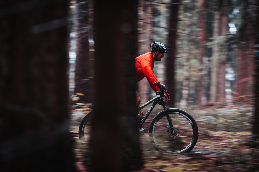 man in red jacket riding bicycle in forest during daytime