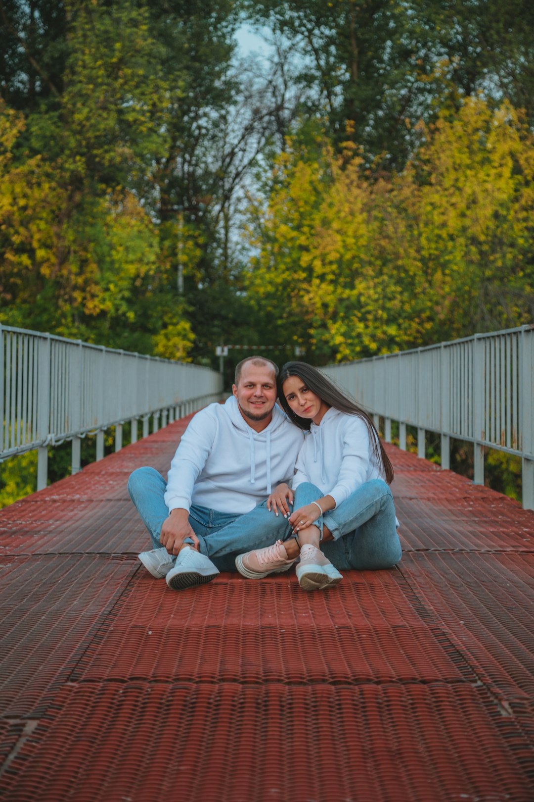 man and woman sitting on brown wooden bridge during daytime