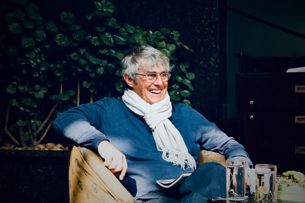 man in blue sweater sitting on brown wooden armchair