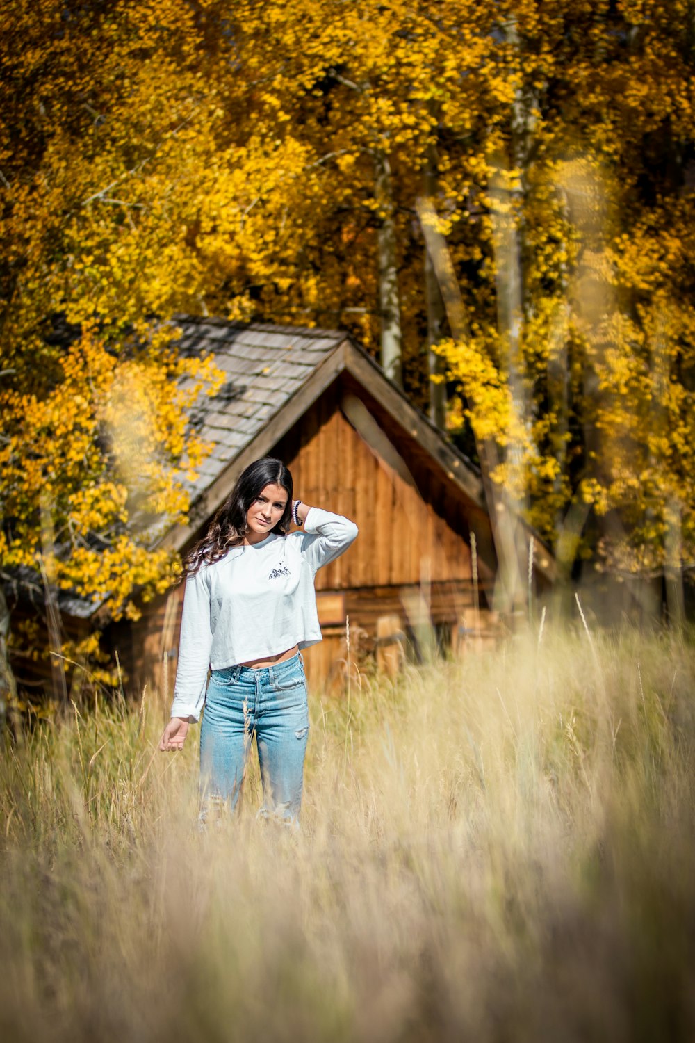 woman in white long sleeve shirt and blue denim jeans standing on green grass field during