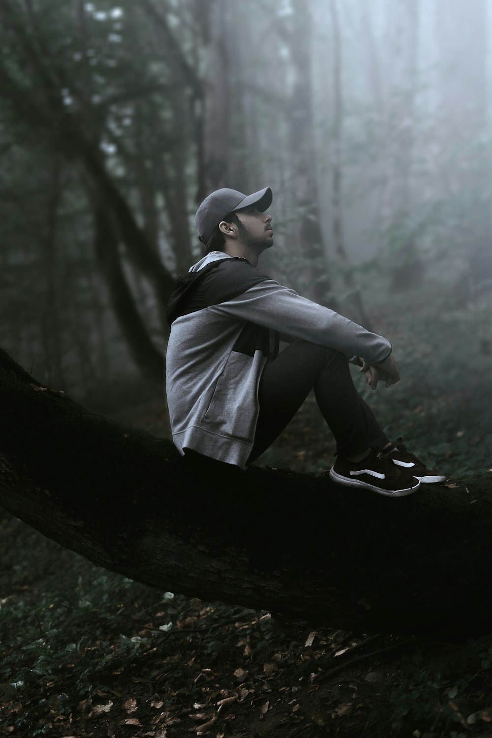 man in black leather jacket and black hat sitting on tree log