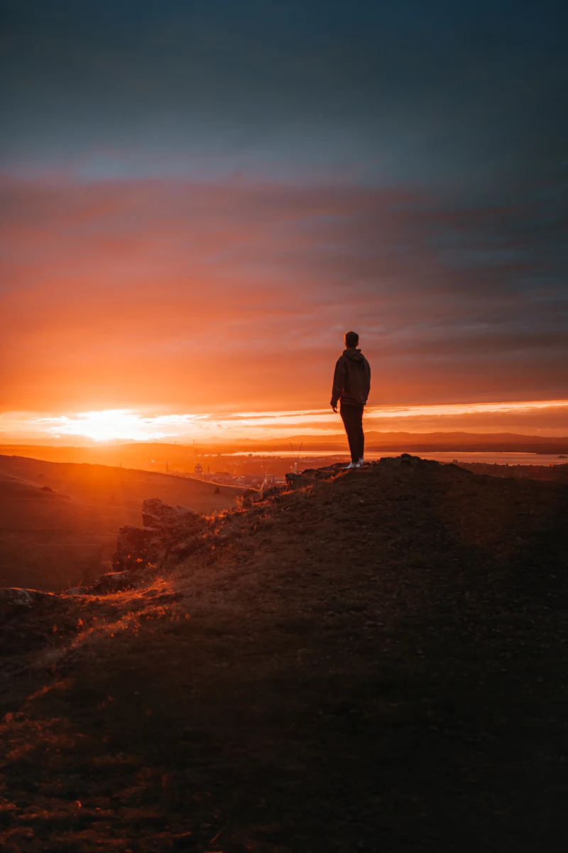 A man walking along the shore toward the rising sun