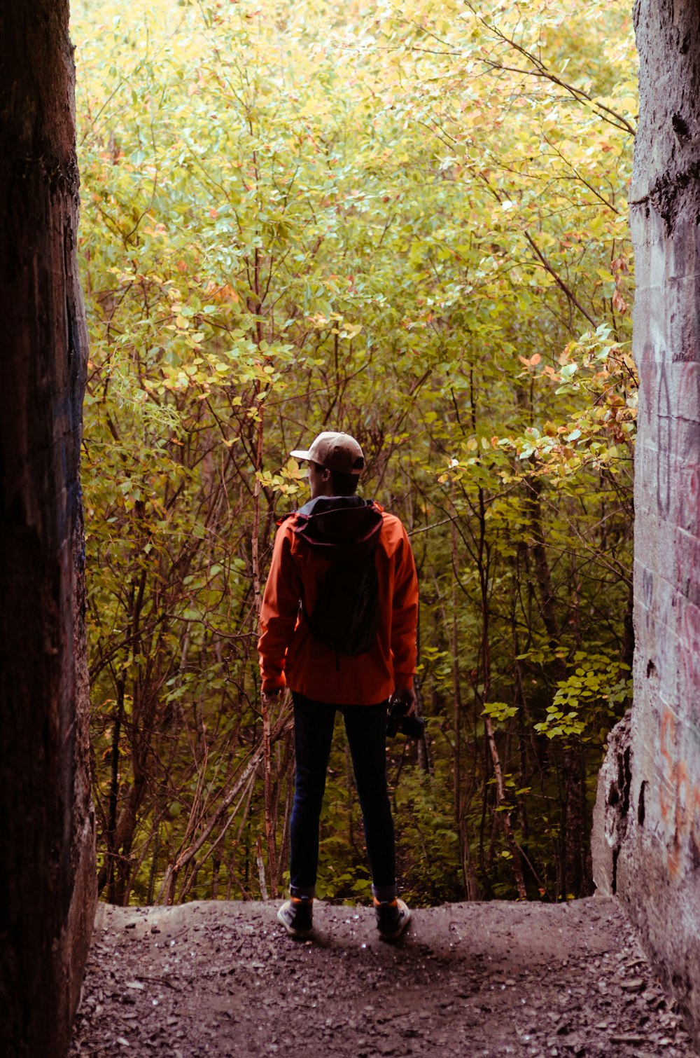 man in red jacket and black pants standing in the middle of forest during daytime