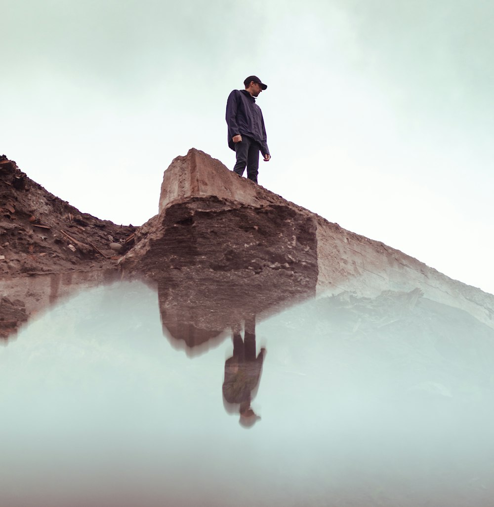 man in black jacket standing on brown rock formation during daytime