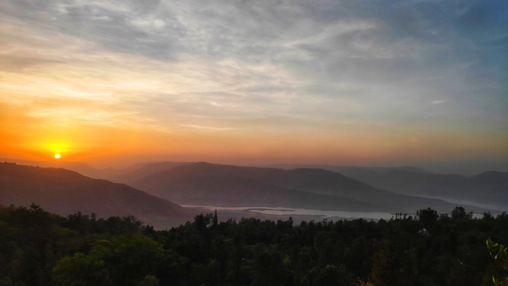 Árboles verdes cerca de la montaña durante la puesta del sol