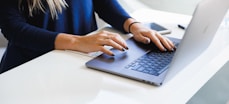 woman in blue long sleeve shirt using macbook pro