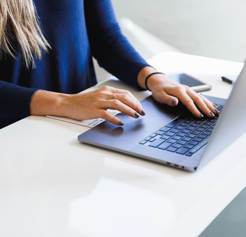 woman in blue long sleeve shirt using macbook pro