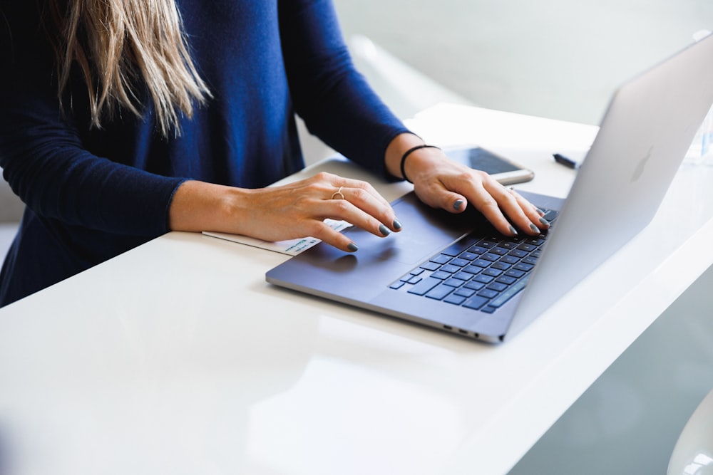 woman in blue long sleeve shirt using macbook pro