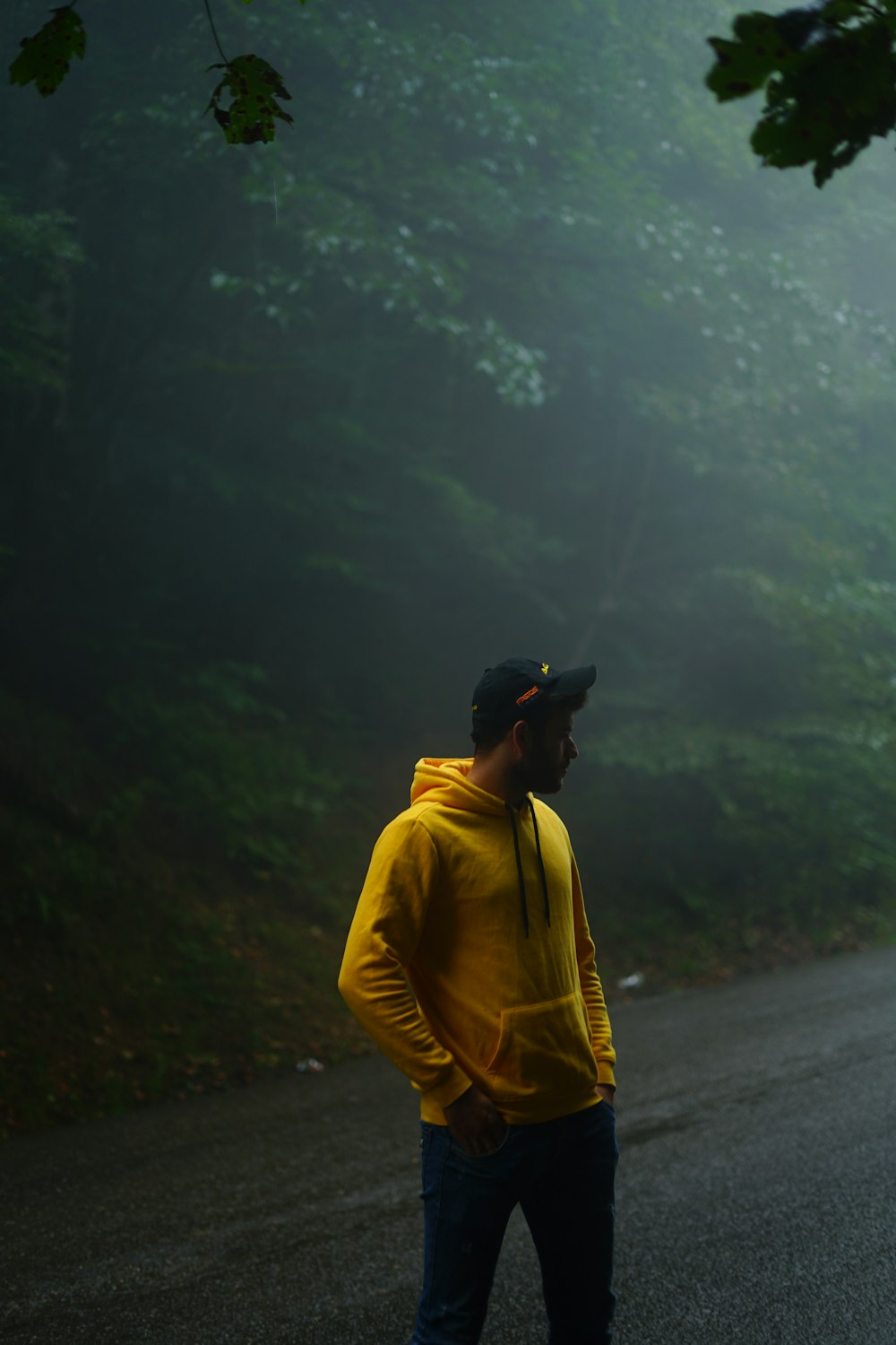 man in yellow jacket and black cap standing on road during daytime