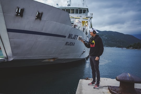 man in black jacket and black pants standing on concrete dock near white ship during daytime in Ploče Croatia