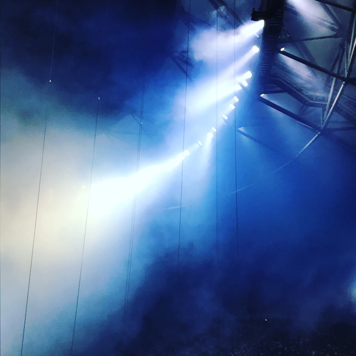 Beams of blue light cutting through haze above an empty stage