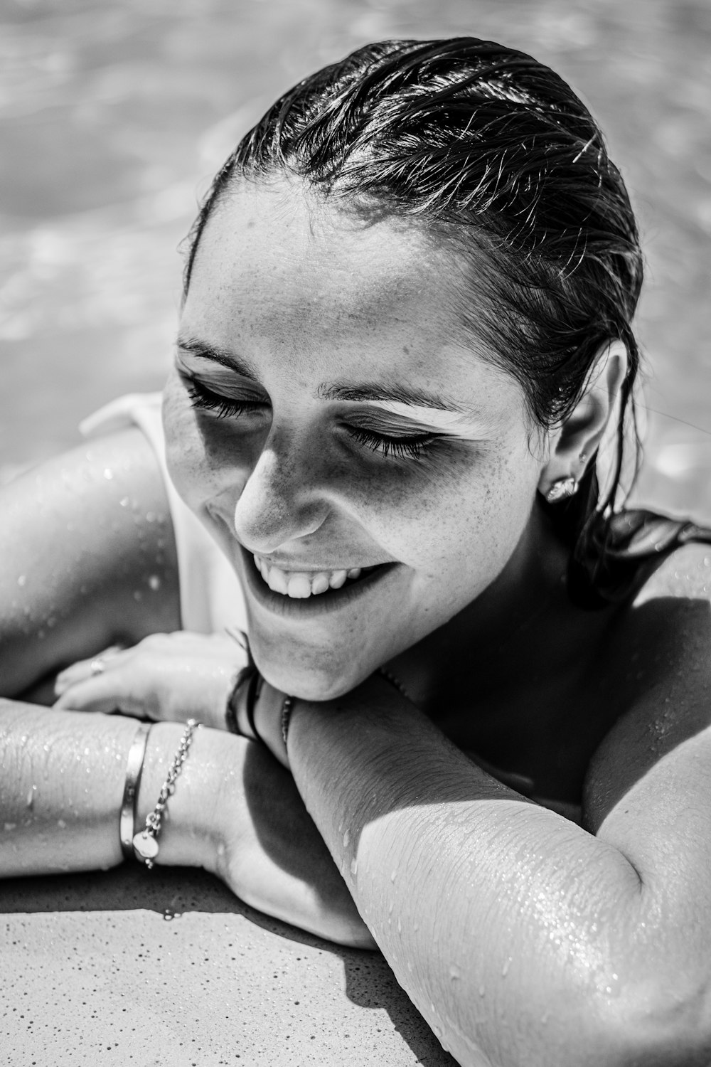 grayscale photo of smiling woman wearing beaded bracelet